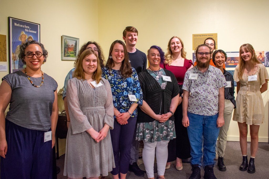 Emily's museum studies professor and 10 classmates stand in front of their exhibition space.